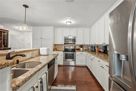 a kitchen with granite countertop a sink stainless steel appliances and cabinets