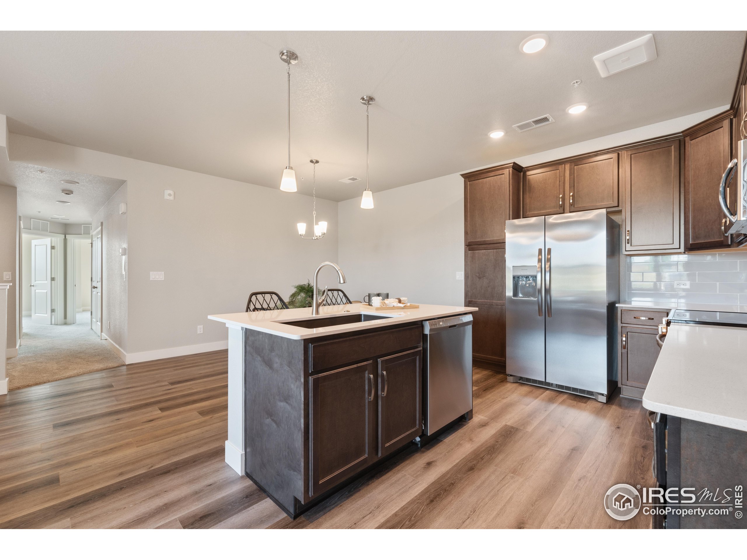6793 Maple Leaf Drive, Unit 101 Timnath, CO 80547 - Photo 2 of 11 a kitchen with stainless steel appliances granite countertop a sink a stove a refrigerator and a microwave