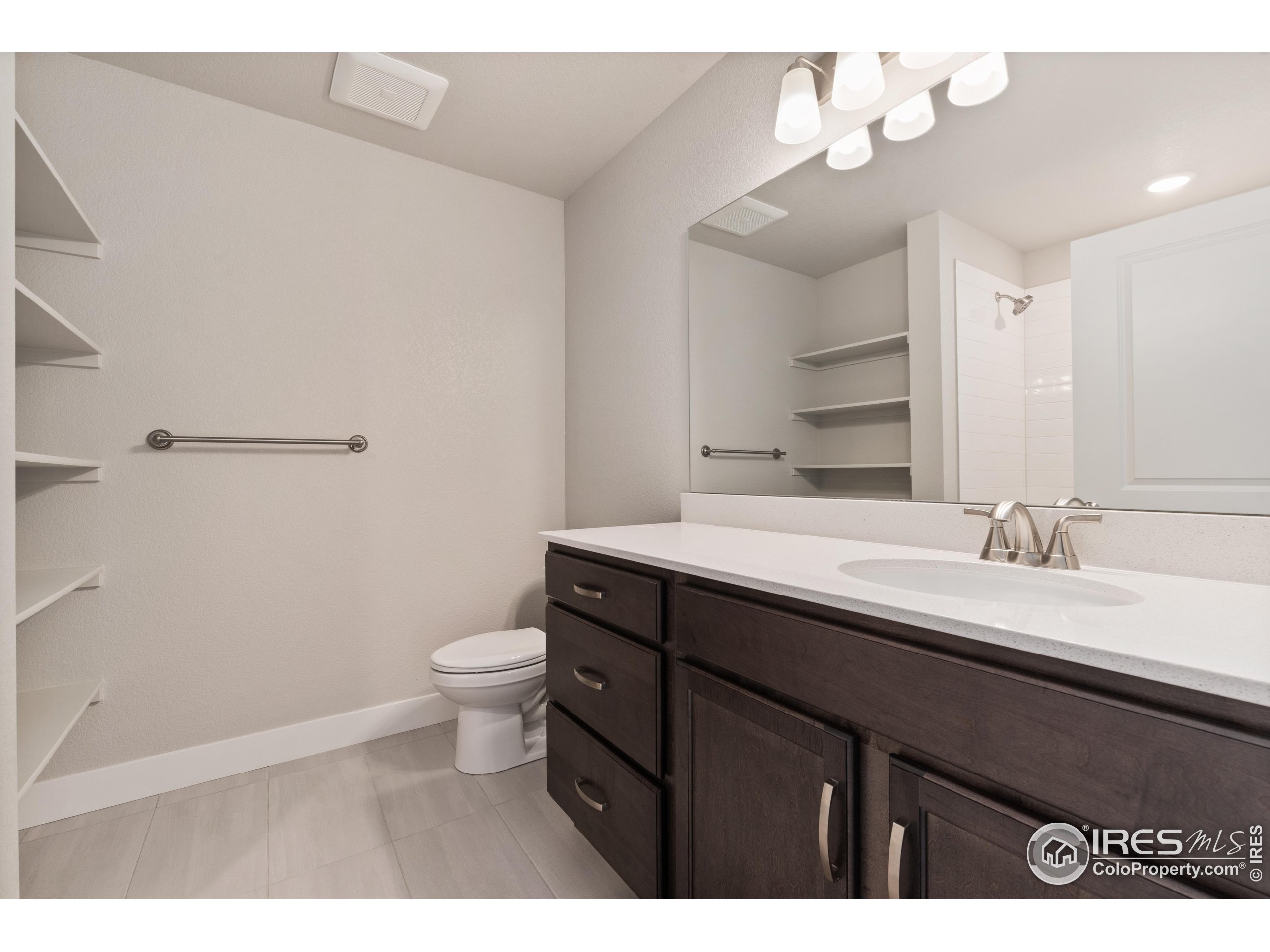 6793 Maple Leaf Drive, Unit 101 Timnath, CO 80547 - Photo 6 of 11 a bathroom with a granite countertop sink a toilet and a mirror