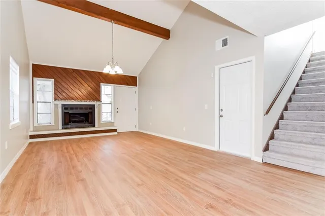 a view of an empty room with wooden floor fireplace and a window