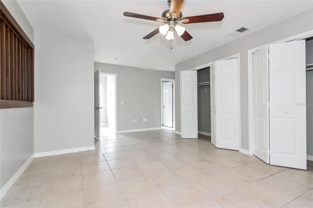 an empty room with closet and a ceiling fan