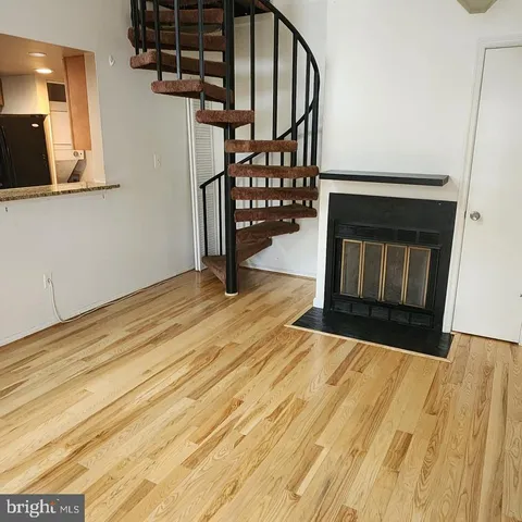 a view of an empty room with wooden floor and a fireplace