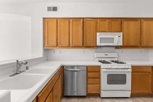 a kitchen with stainless steel appliances granite countertop white cabinets a stove and a sink