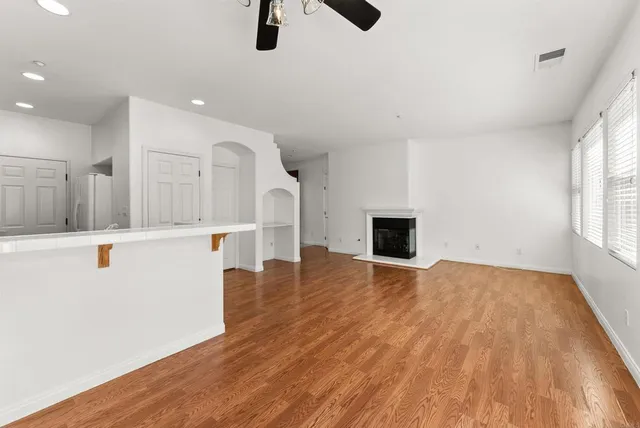 a view of an empty room with window and wooden floor