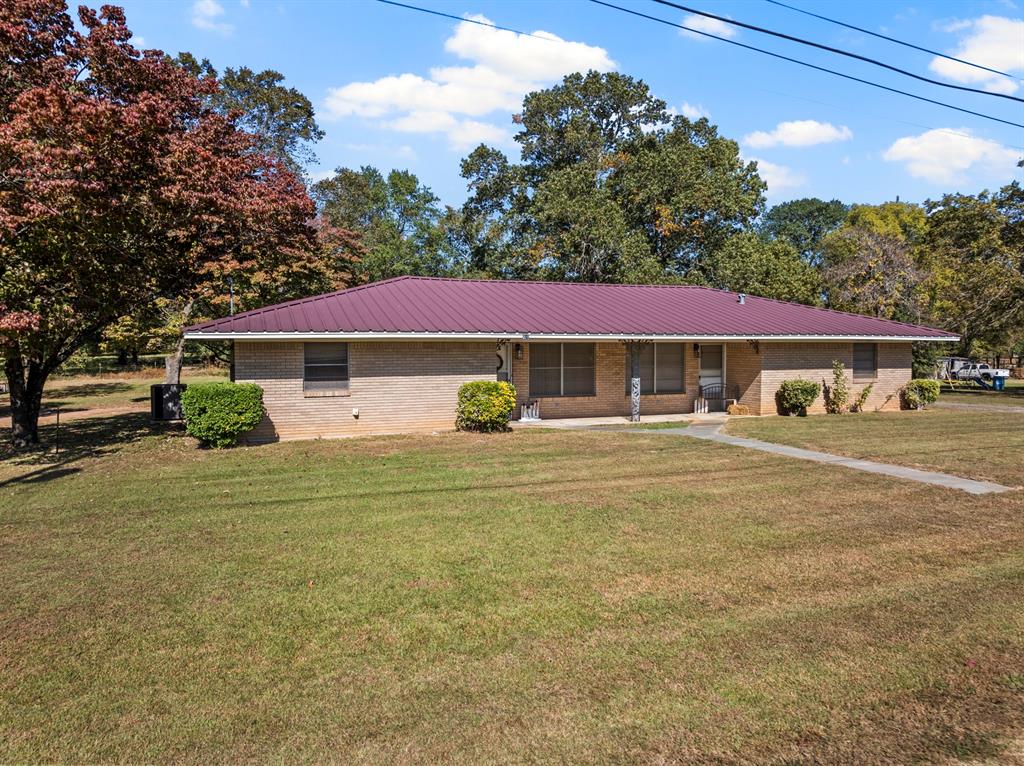 Ranch-style house with brick siding, metal roof, and a front yard