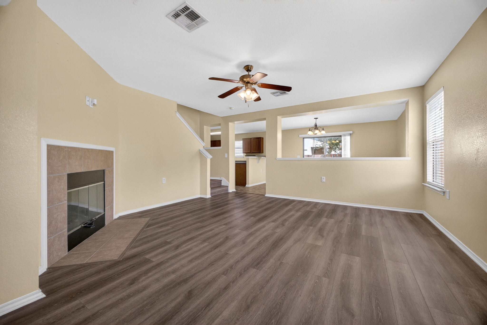 8813 Wiley Way Austin, TX 78747 - Photo 5 of 39 Laminated flooring flows throughout this well-lit living area, featuring a cozy fireplace and a ceiling fan for comfort.