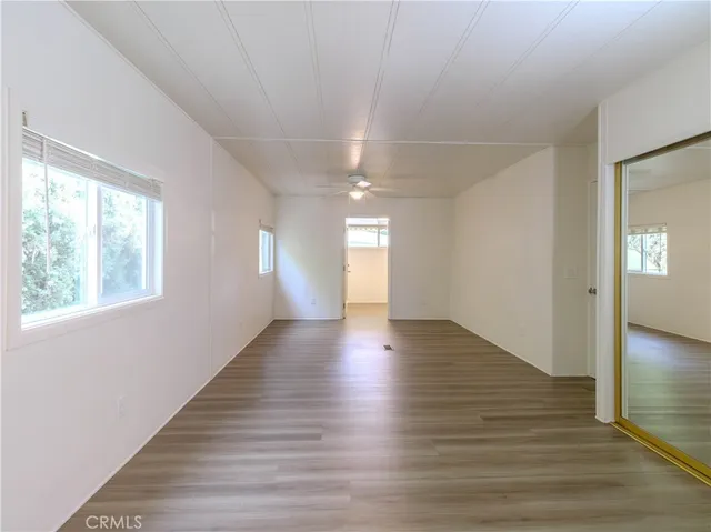 a view of empty room with wooden floor and fan