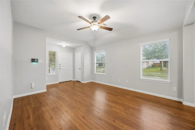 a view of an empty room with wooden floor and a window