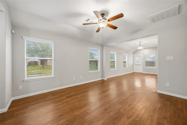 a view of an empty room with wooden floor and a window