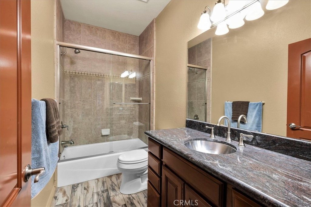 7959 Stephenson Lane Yucca Valley, CA 92284 - Photo 48 of 75 a bathroom with a granite countertop sink a toilet a mirror and shower