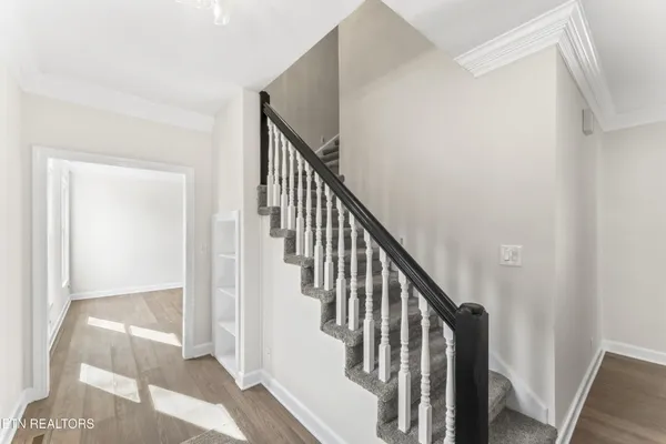 a view of staircase with wooden floor and white walls
