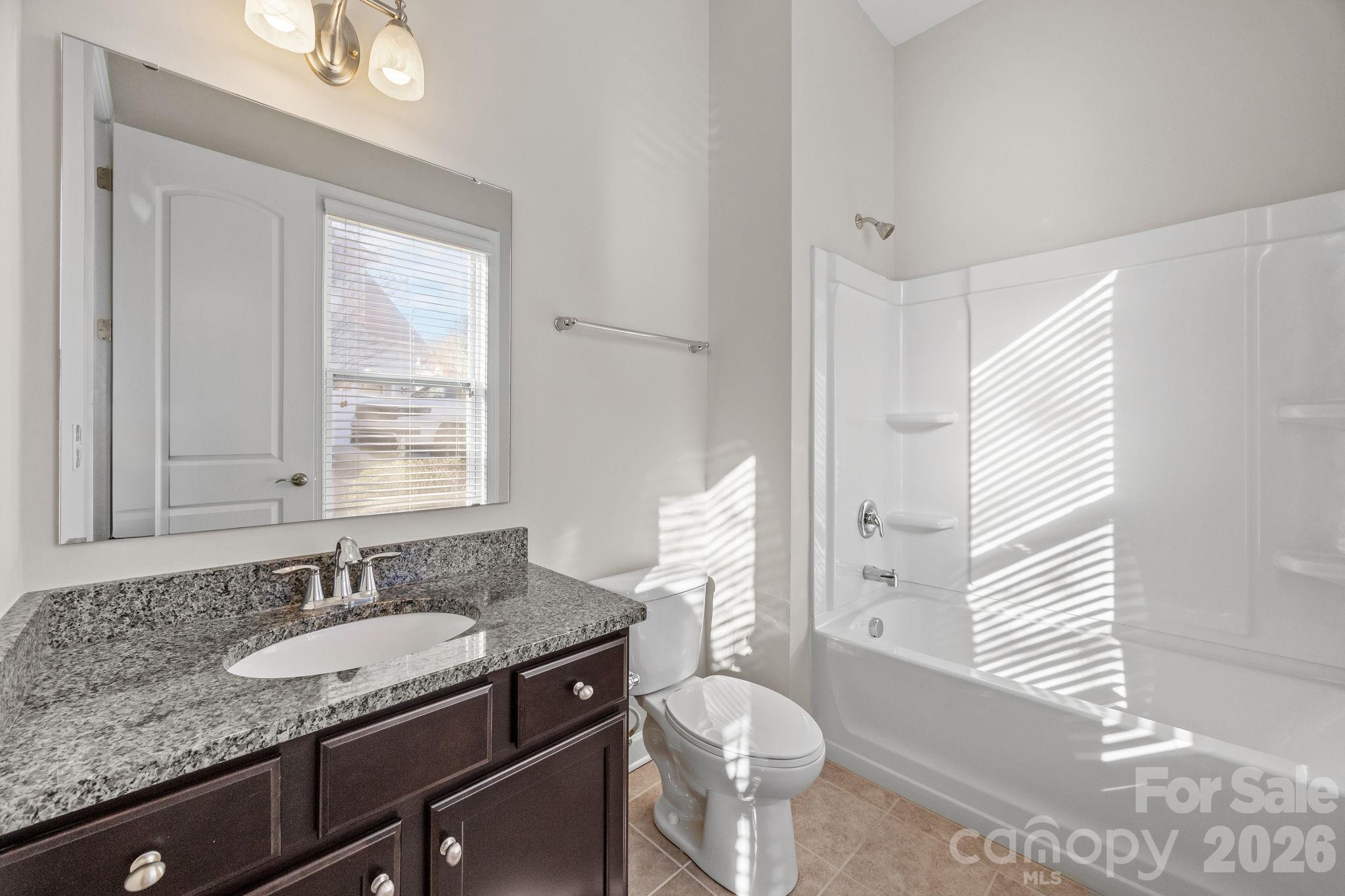 1221 Violet Court Fort Mill, SC 29708 - Photo 24 of 48 a bathroom with a granite countertop sink toilet a mirror and a window