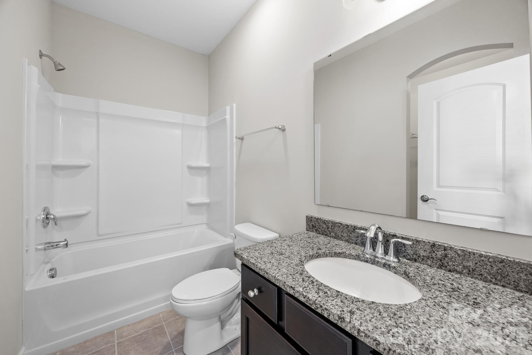 1221 Violet Court Fort Mill, SC 29708 - Photo 27 of 48 a bathroom with a granite countertop toilet a sink and a bathtub