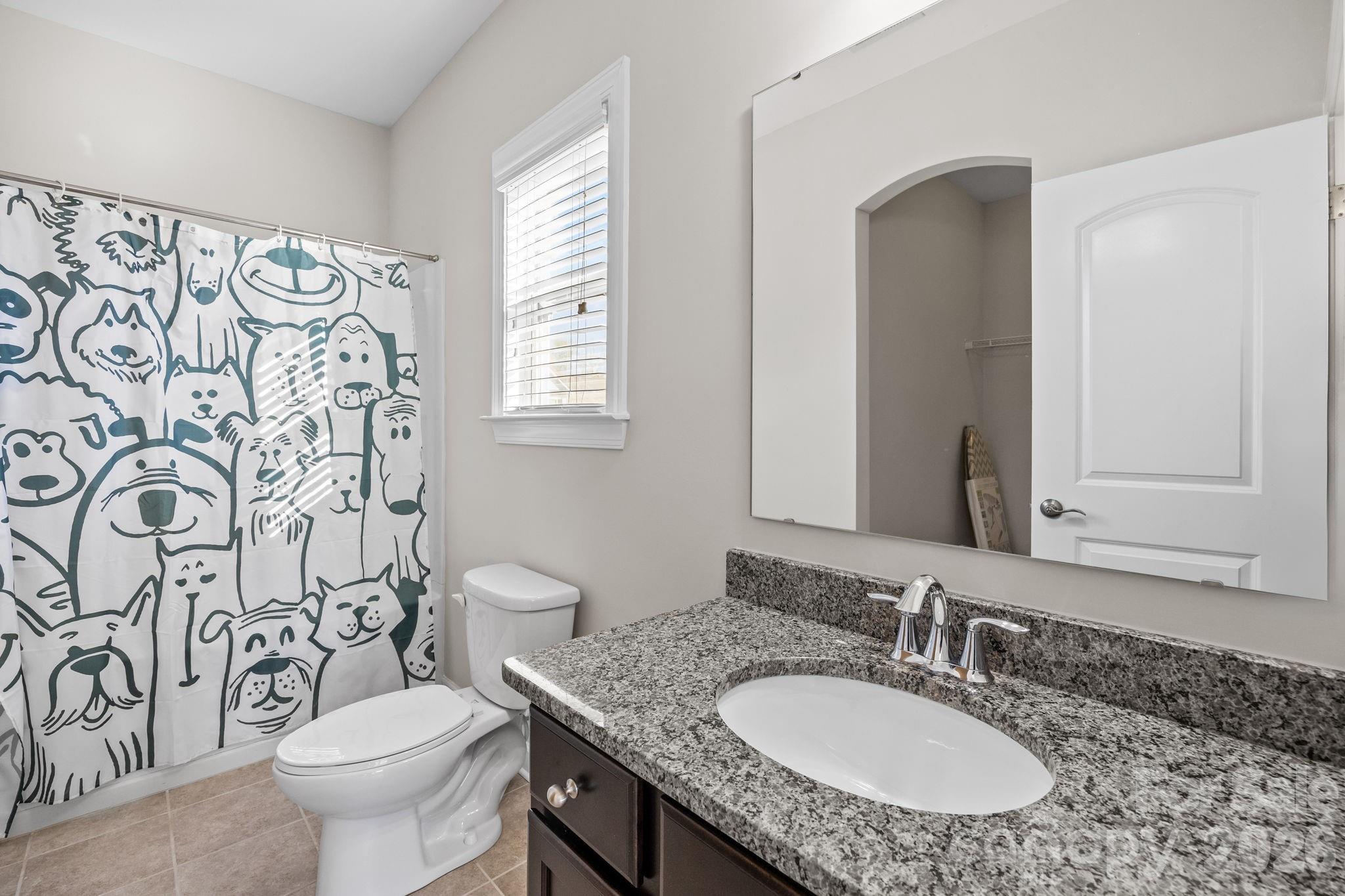 1221 Violet Court Fort Mill, SC 29708 - Photo 38 of 48 a bathroom with a granite countertop toilet a sink a mirror a window and a shower