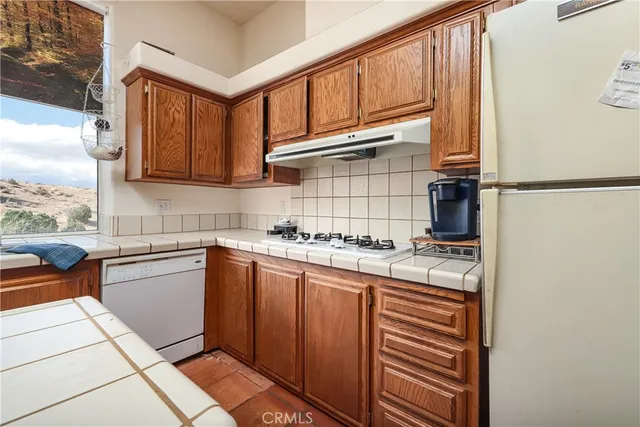 a kitchen with stainless steel appliances granite countertop a refrigerator a sink dishwasher a stove and white countertops with cabinets