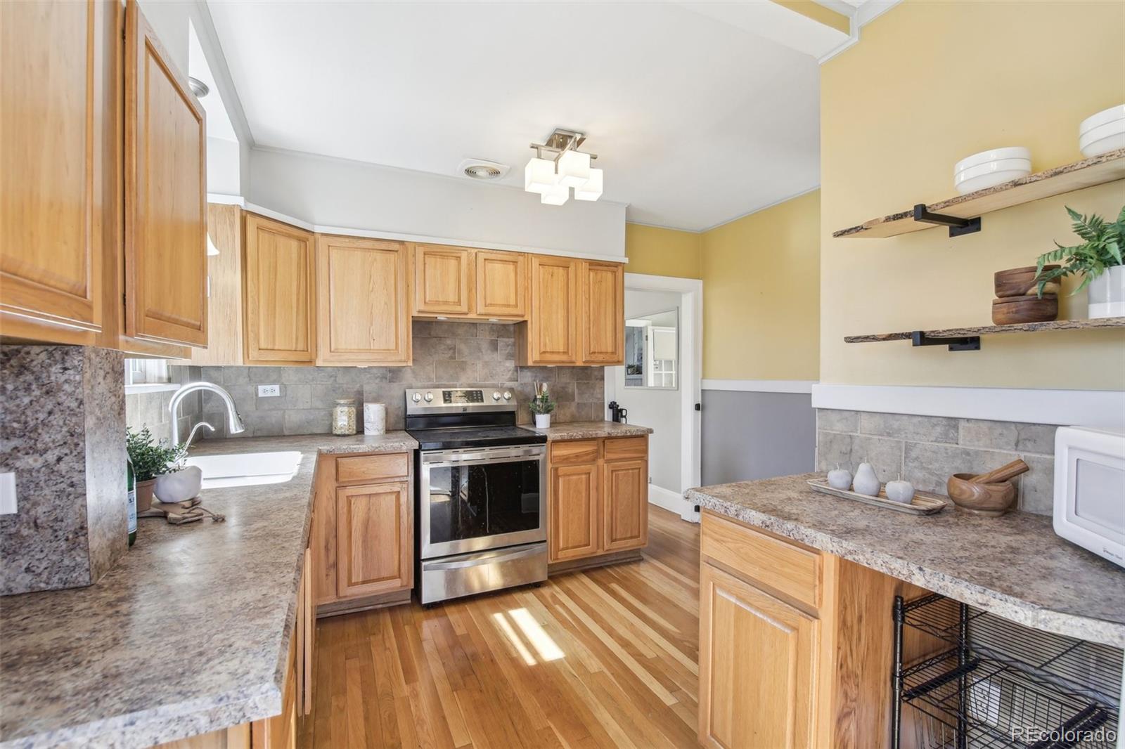 1462 Eudora Street Denver, CO 80220 - Photo 12 of 38 a kitchen with stainless steel appliances granite countertop a sink stove and cabinets