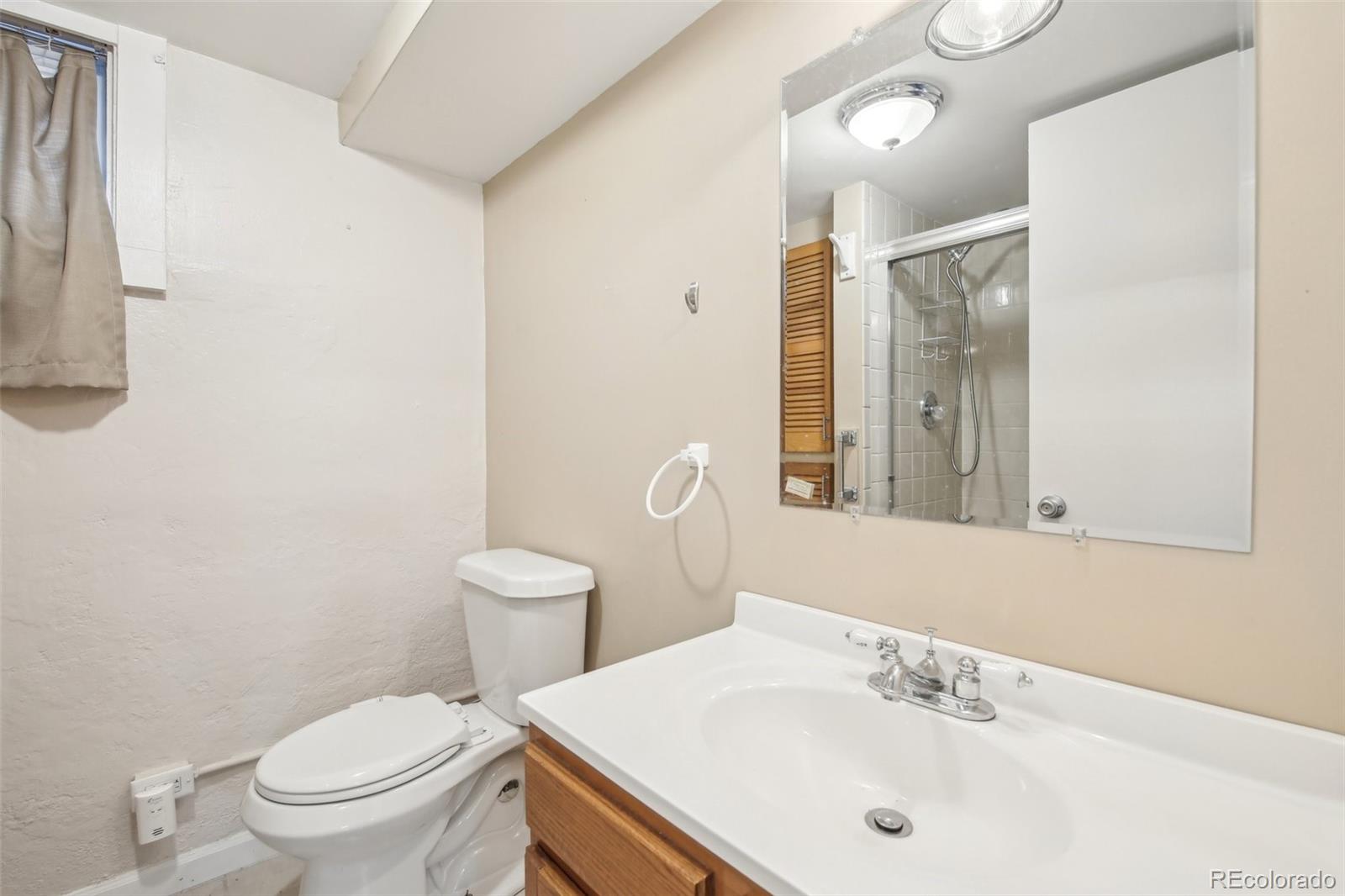 1462 Eudora Street Denver, CO 80220 - Photo 24 of 38 a bathroom with a sink a toilet and a mirror