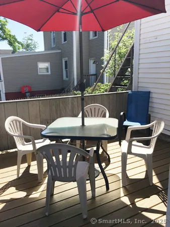 a view of a patio with table and chairs under an umbrella with wooden floor