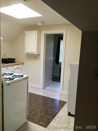 a view of a kitchen with refrigerator and white cabinets