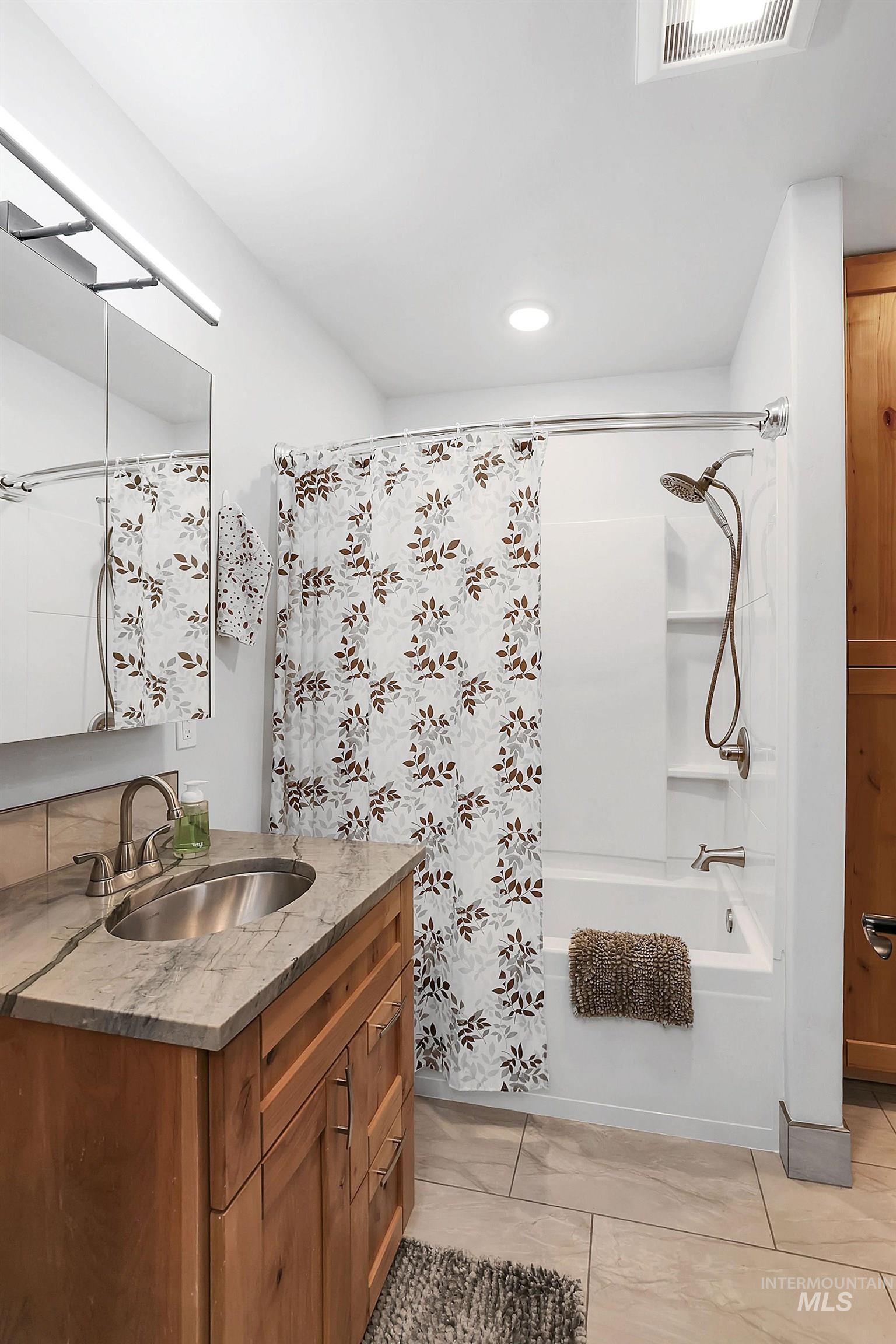 715 Spruce Street McCall, ID 83638 - Photo 17 of 37 Full bathroom featuring vanity, shower / tub combo with curtain, light tile patterned floors, and recessed lighting