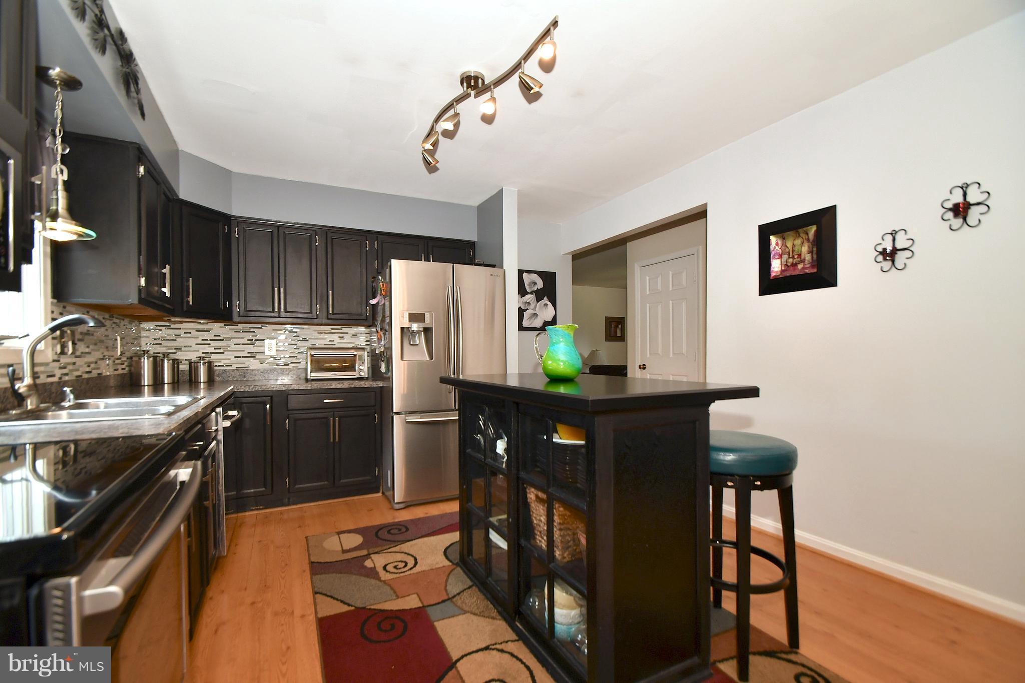 8126 Old Philadelphia Road Baltimore, MD 21237 - Photo 7 of 30 a kitchen with stainless steel appliances granite countertop a refrigerator a stove a sink dishwasher and microwave with wooden cabinets
