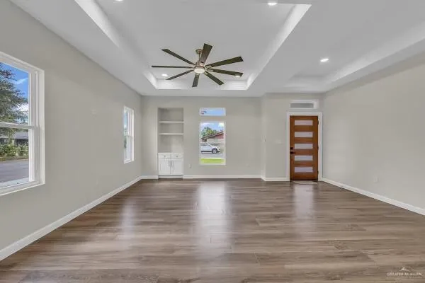 a view of an empty room with a window and wooden floor