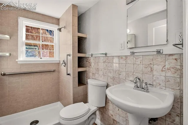 a bathroom with a sink a toilet and shower