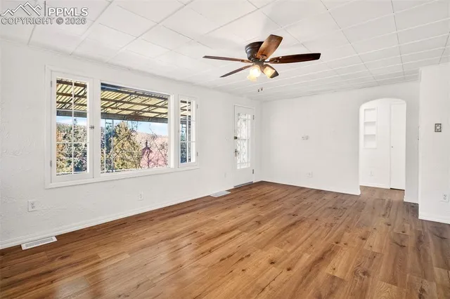 a view of empty room with wooden floor and fan