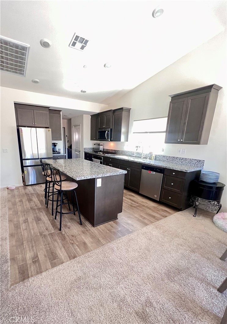 31381 Linden Flower Road Winchester, CA 92596 - Photo 6 of 33 a kitchen with stainless steel appliances kitchen island granite countertop a sink counter space and cabinets