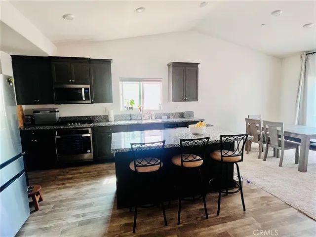 a large kitchen with granite countertop a stove a sink a table and chairs