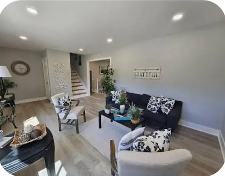 a living room with furniture couches and a dining table with wooden floor