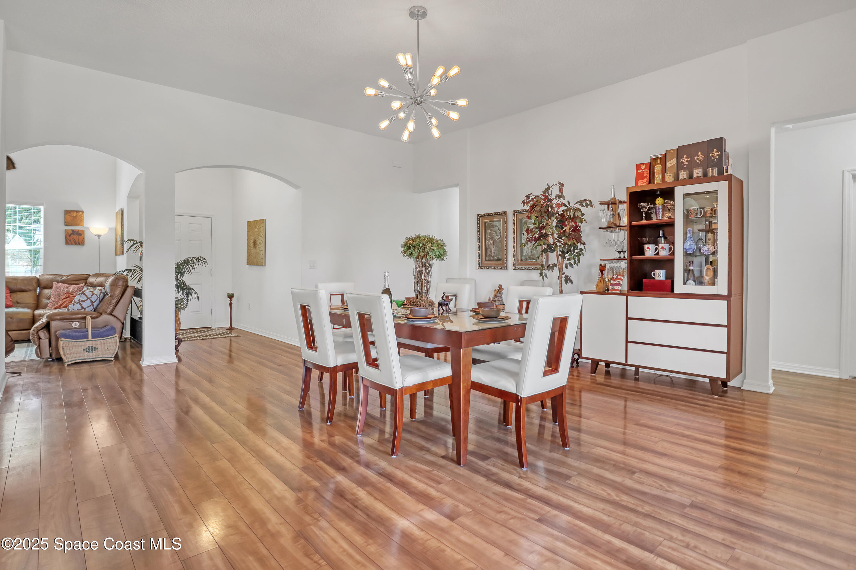 1121 Morgan Circle Northeast Palm Bay, FL 32905 - Photo 14 of 61 a dining room with furniture wooden floor a rug a potted plant and a chandelier