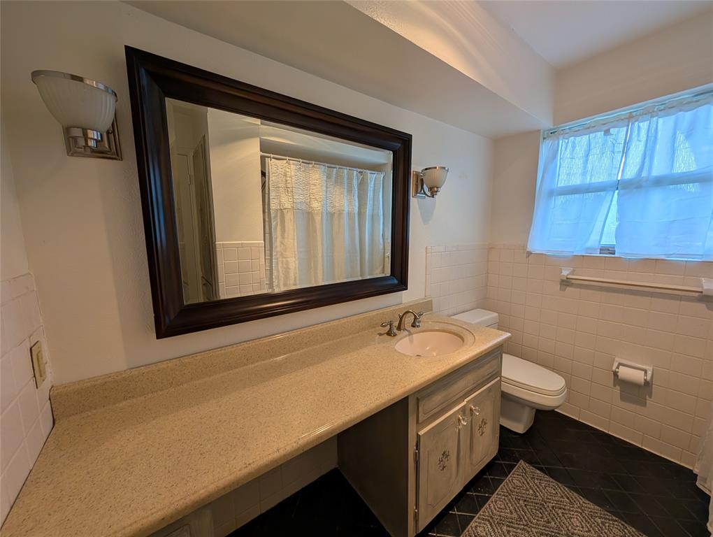 4715 Skillman Street, Unit A Dallas, TX 75206 - Photo 17 of 28 Bathroom featuring a vanity with an integrated sink, a dark framed mirror, and wall-mounted sconces