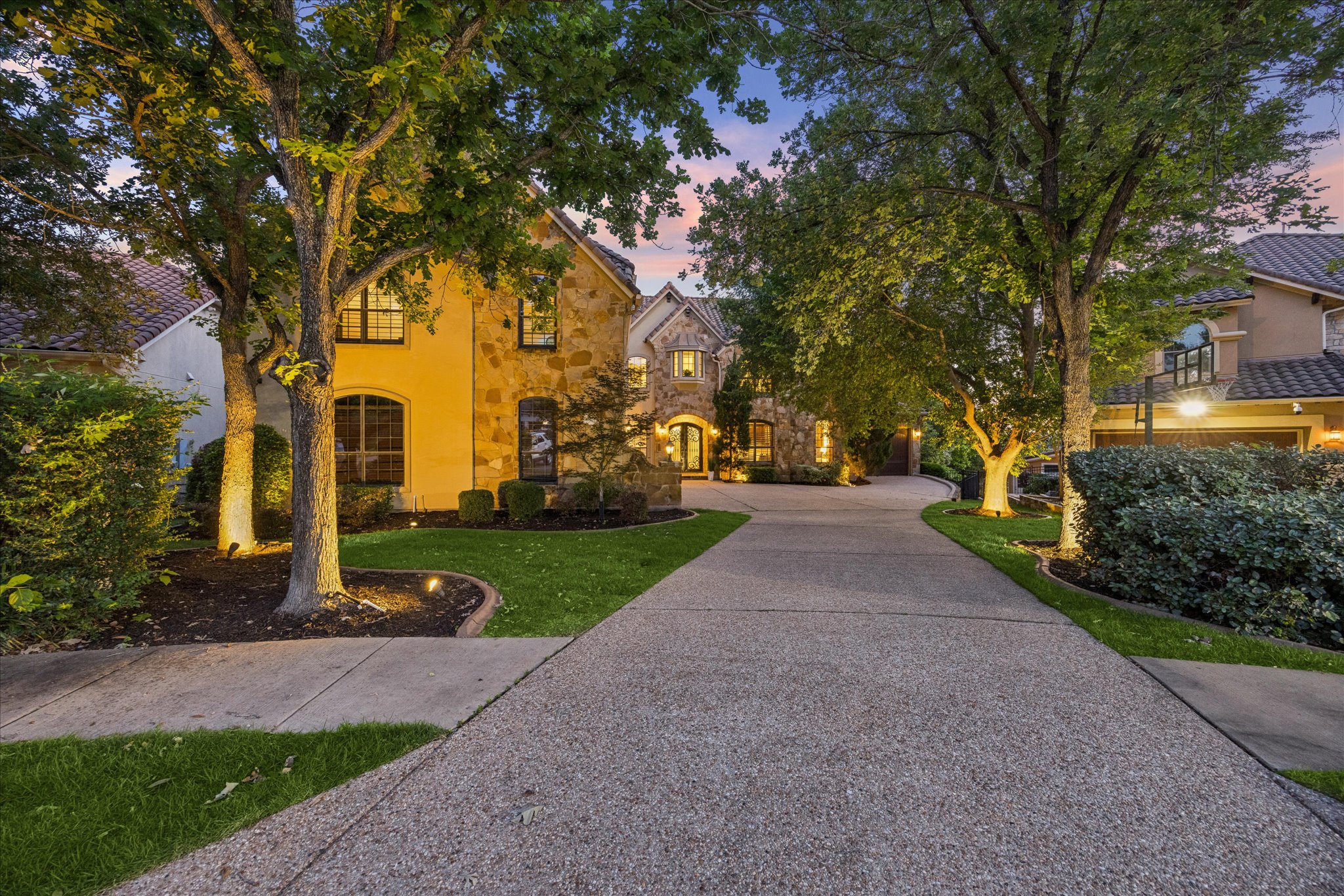 11805 Ranchview Court Austin, TX 78732 - Photo 2 of 36 Expansive concrete driveway leading to a stone and stucco façade residence with multiple mature trees