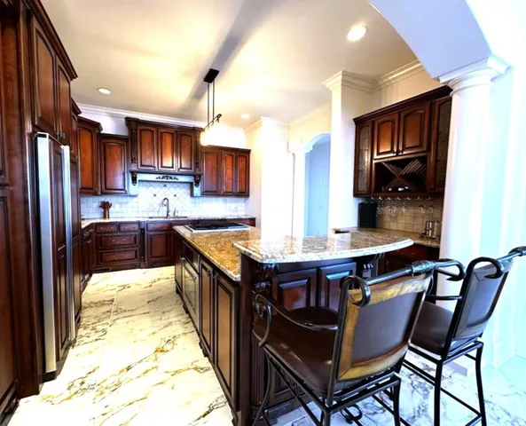 a kitchen with stainless steel appliances granite countertop a table chairs a sink and a refrigerator