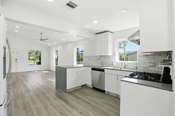 an empty room with wooden floor ceiling fan and windows