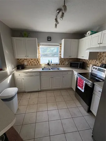 a kitchen with granite countertop a sink a stove top oven and cabinets