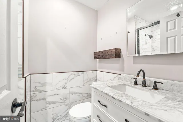 a bathroom with a granite countertop sink a toilet and mirror