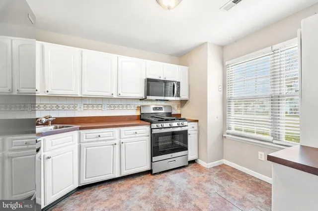 a kitchen with white cabinets and appliances