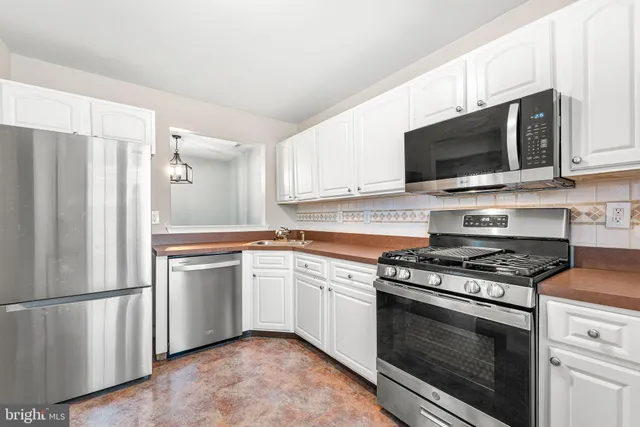 a kitchen with stainless steel appliances white cabinets white stove a microwave and a refrigerator