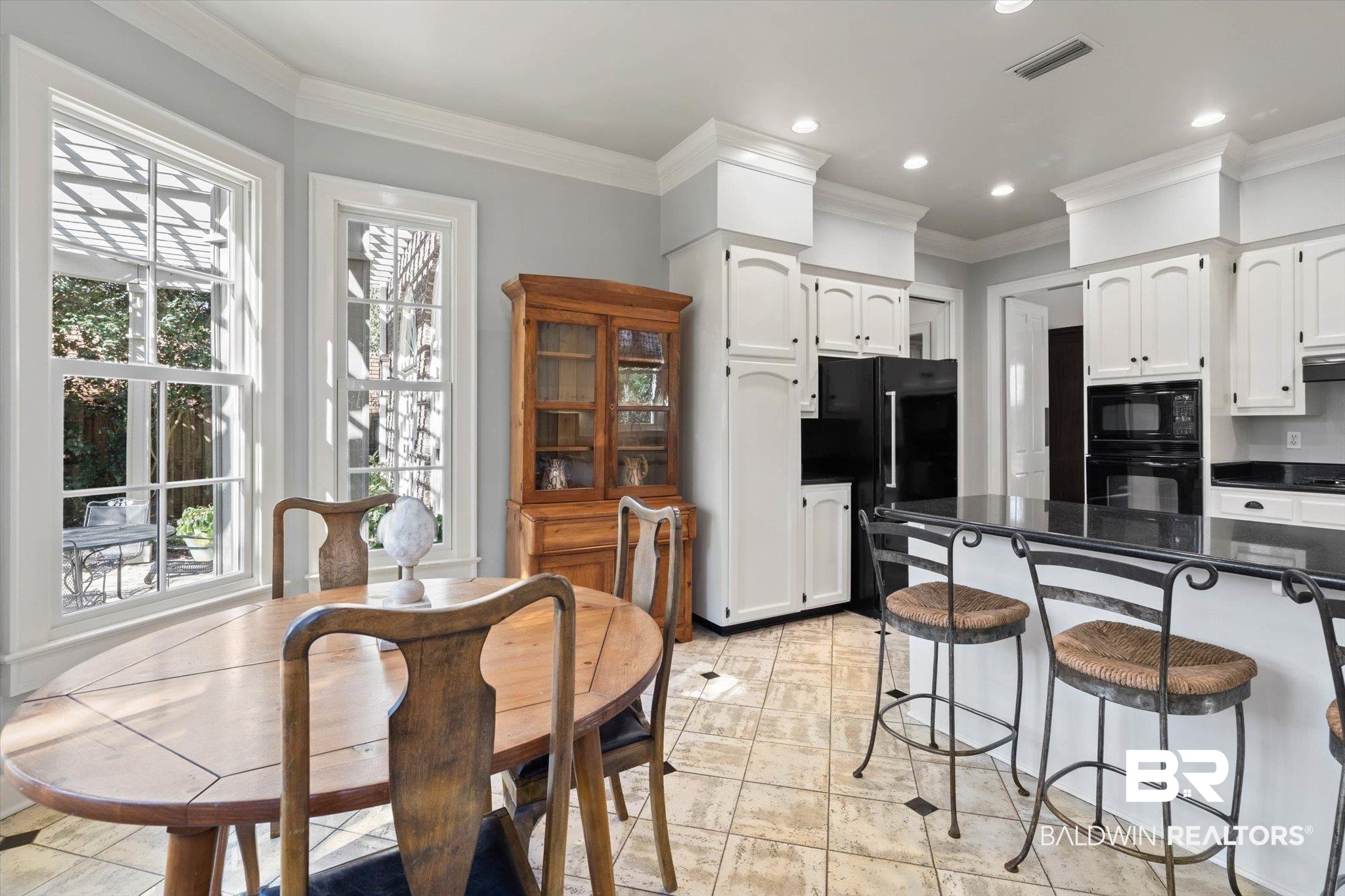 3615 Stein Street Mobile, AL 36608 - Photo 15 of 44 Kitchen featuring ornamental molding, white cabinets, black appliances, a breakfast bar, and dark stone countertops