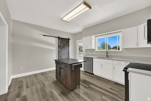 716 East Factory Street Garland, UT 84312 - Photo 15 of 30 Kitchen featuring white cabinetry, light countertops, stainless steel dishwasher, wood-finish flooring, and a sliding barn door