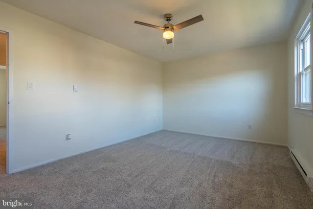 an empty room with a window and a ceiling fan