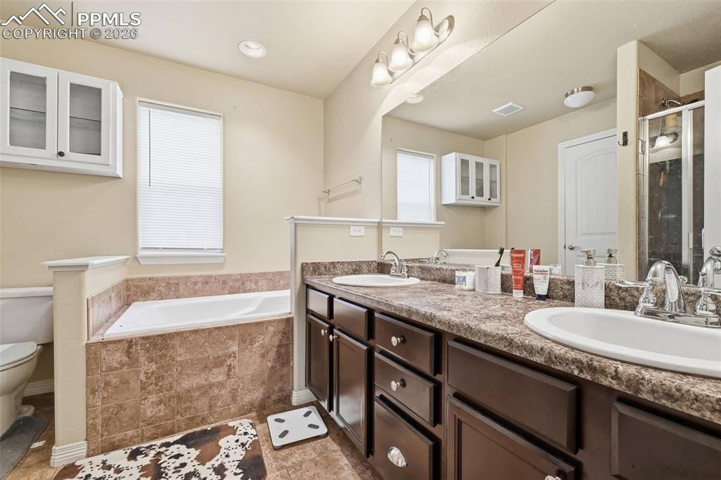 6186 Pilgrimage Road Colorado Springs, CO 80925 - Photo 17 of 20 a bathroom with a granite countertop bathtub sink vanity mirror and toilet