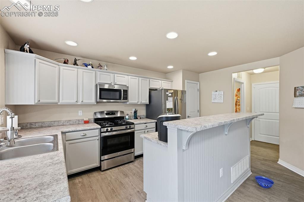 6186 Pilgrimage Road Colorado Springs, CO 80925 - Photo 7 of 20 a kitchen with stainless steel appliances granite countertop a stove top oven a sink and white cabinets