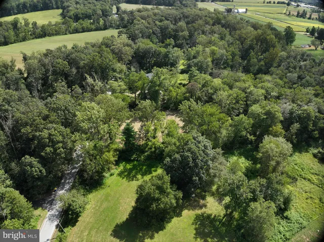 an aerial view of residential house with outdoor space and trees all around