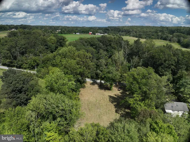 an aerial view of residential house with outdoor space and trees all around