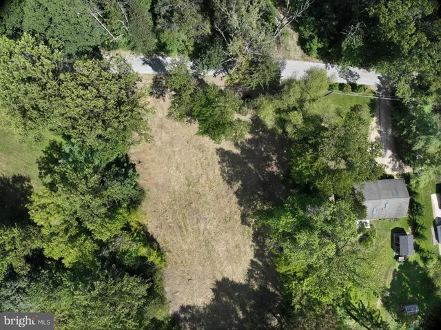 an aerial view of residential house with outdoor space and trees all around