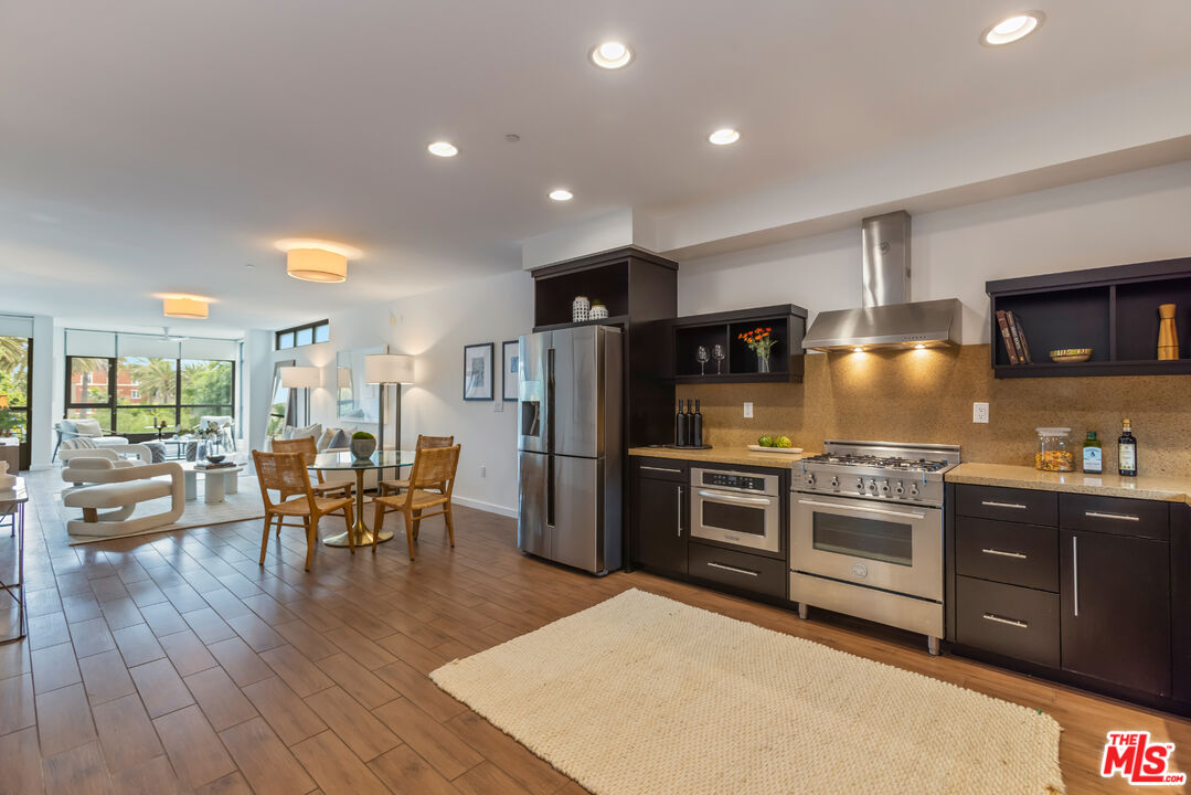 13045 Pacific Promenade, Unit 330 Los Angeles, CA 90094 - Photo 2 of 43 a kitchen with stainless steel appliances granite countertop a stove top oven a sink dishwasher a dining table and chairs with wooden floor