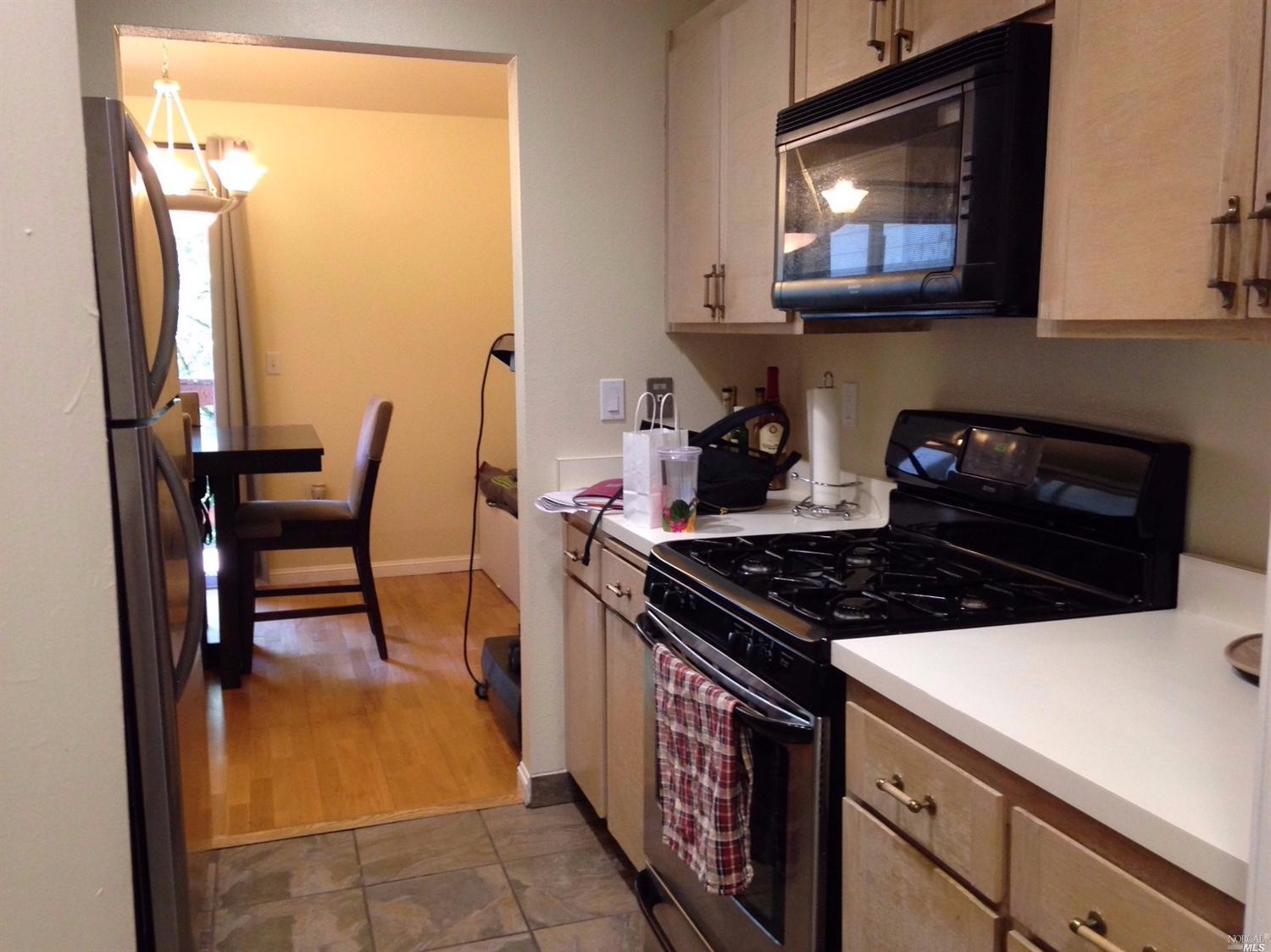 427 Enfrente Road, Unit B Novato, CA 94949 - Photo 1 of 1 a kitchen with stainless steel appliances a stove a microwave and a dining table with wooden floor